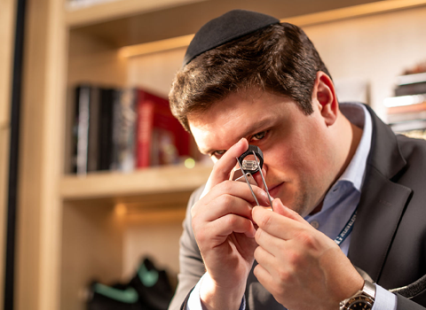 A man is observing diamonds with a magnifying lens